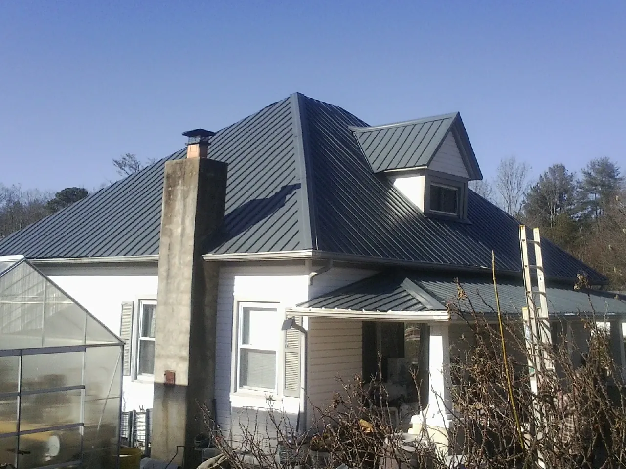 Dark blue standing seam metal roof on a white farmhouse with dormer — Slate & Tile Roof Repair by Roofing Brothers in Etlan