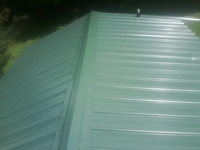 New green metal panels meeting at the ridge of a roof — Flat Roof Repair work by our crew in Etlan