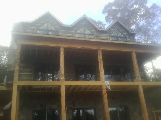 Dormers and porch framing on a large log home under construction — Roof Coating work by our crew in Etlan