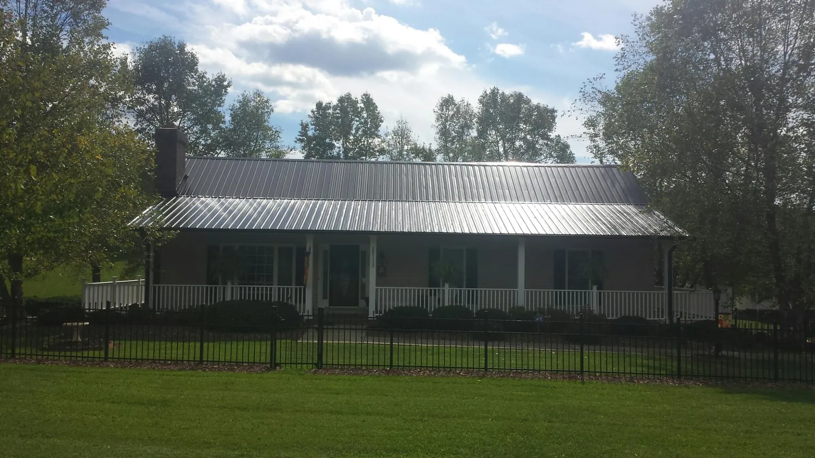 Gray metal roof on a brick ranch with a full width front porch — Gutter Guard Installation work by our crew in Etlan