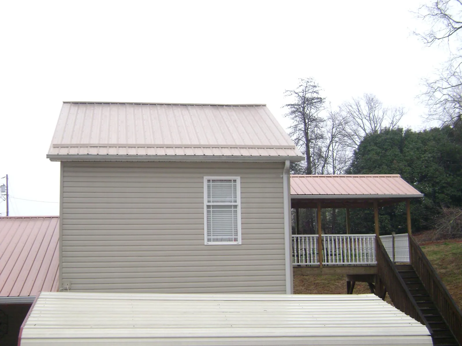 Tan metal roofs on a two story addition and attached porch, from a Roof Replacement job in Etlan